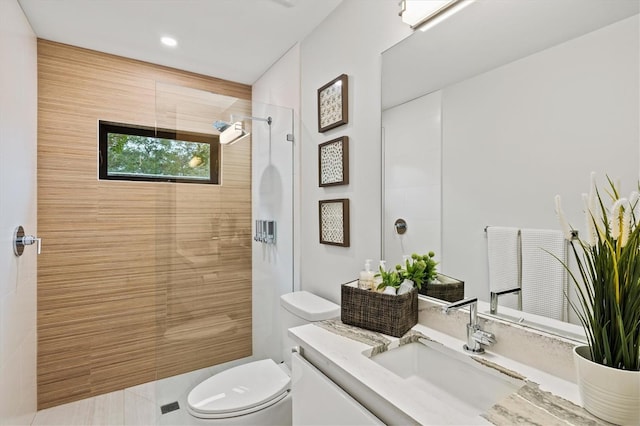 bathroom featuring toilet, vanity, and a tile shower