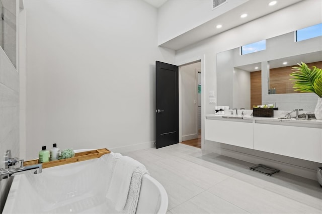 bathroom featuring a washtub, tile patterned floors, vanity, and a towering ceiling