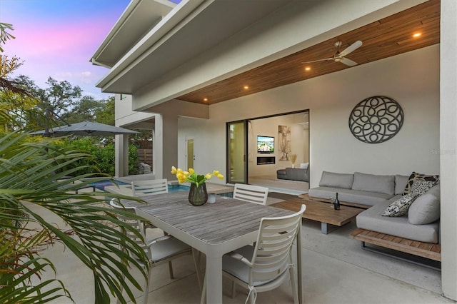 patio terrace at dusk featuring ceiling fan and an outdoor living space