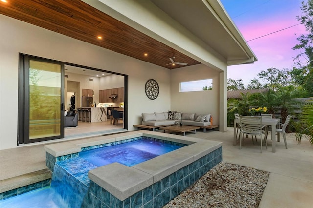 pool at dusk featuring an outdoor living space, a patio, and an in ground hot tub