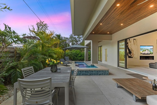 patio terrace at dusk featuring an in ground hot tub