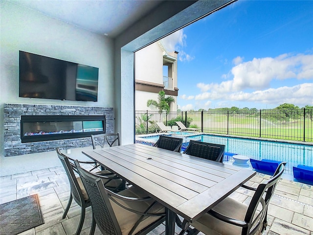 view of patio / terrace featuring an outdoor stone fireplace and a fenced in pool