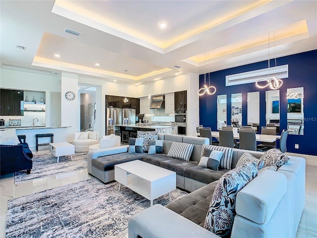 living room with a raised ceiling and sink