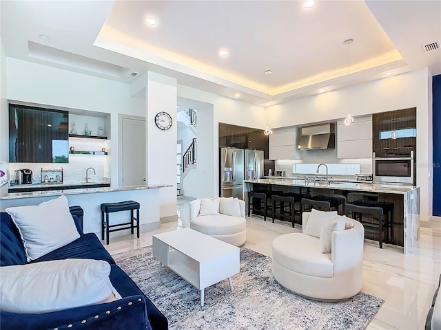 living room featuring a raised ceiling and sink