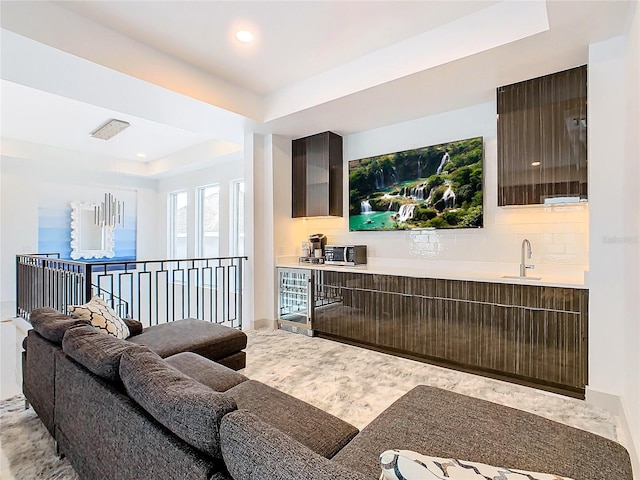 living room featuring a tray ceiling and sink