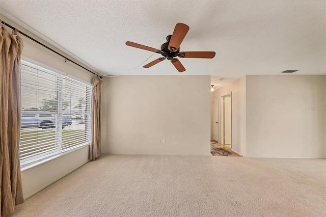 spare room with light carpet, ceiling fan, and a textured ceiling