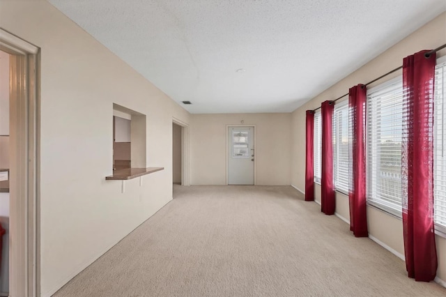 spare room with a textured ceiling and light colored carpet