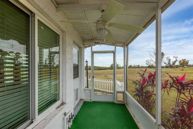 unfurnished sunroom featuring ceiling fan and a rural view