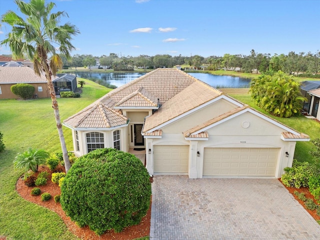 view of front of house featuring a front lawn, a garage, and a water view