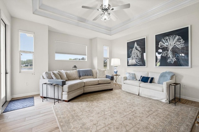 living room featuring a healthy amount of sunlight, light hardwood / wood-style floors, and a tray ceiling