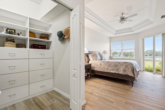 bedroom featuring access to outside, light wood-type flooring, a raised ceiling, and ceiling fan