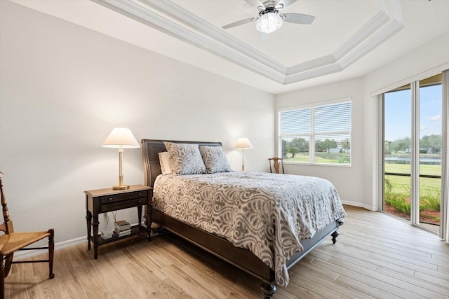 bedroom featuring ceiling fan, a tray ceiling, ornamental molding, and light hardwood / wood-style flooring