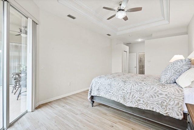 bedroom with a closet, light wood-type flooring, a tray ceiling, ceiling fan, and access to exterior