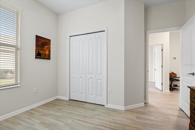 unfurnished bedroom featuring a closet, multiple windows, and light hardwood / wood-style flooring