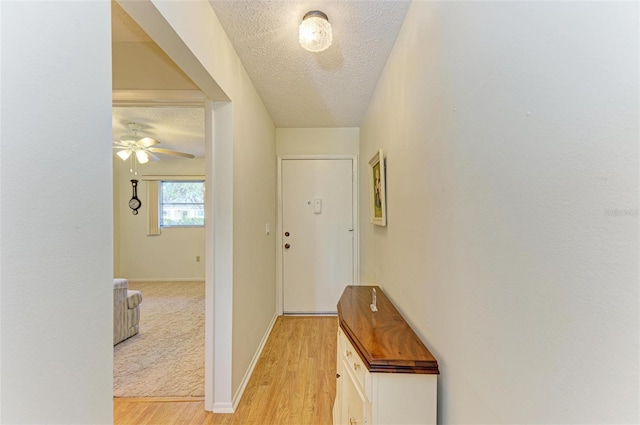 corridor featuring light hardwood / wood-style flooring and a textured ceiling