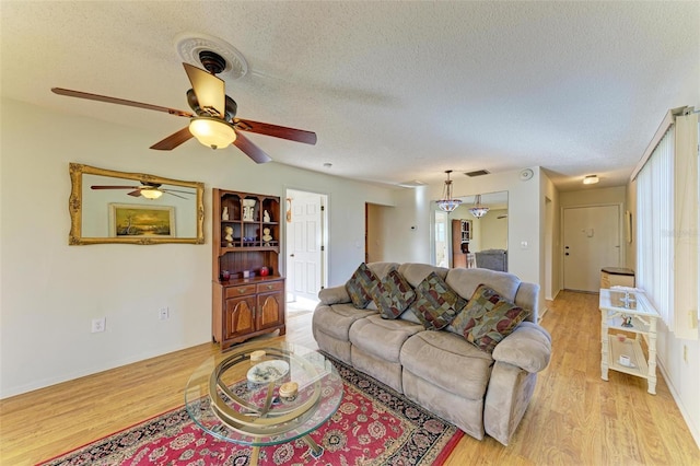 living room with ceiling fan, a textured ceiling, and light hardwood / wood-style flooring