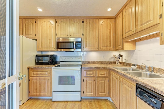 kitchen with light wood-type flooring, white appliances, sink, and tasteful backsplash