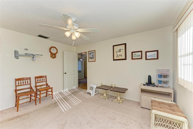 carpeted office space featuring ceiling fan and a textured ceiling