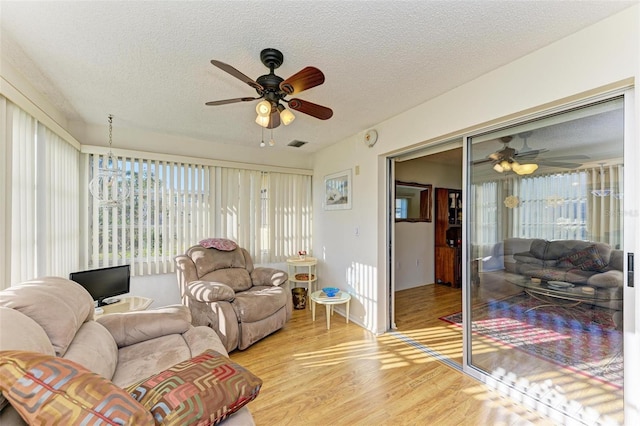 living room featuring ceiling fan, light hardwood / wood-style floors, and a textured ceiling