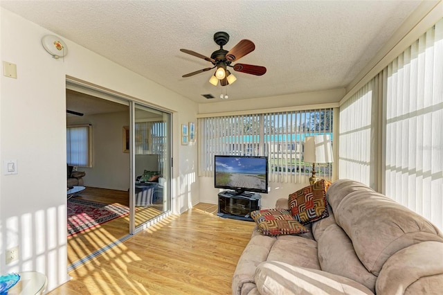 living room with hardwood / wood-style floors, ceiling fan, and a textured ceiling