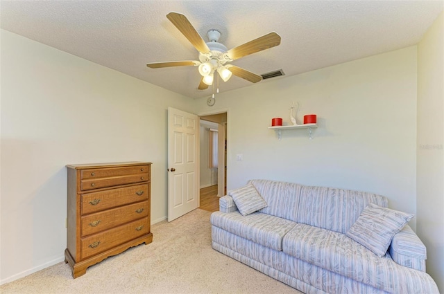 carpeted living room with ceiling fan and a textured ceiling