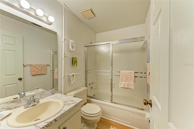 full bathroom with vanity, toilet, wood-type flooring, and bath / shower combo with glass door