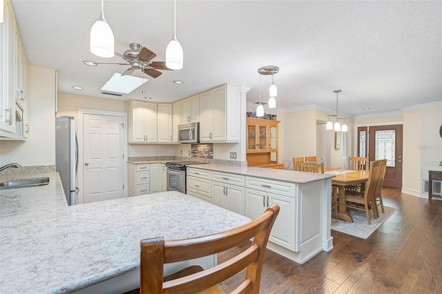 kitchen featuring kitchen peninsula, appliances with stainless steel finishes, hanging light fixtures, and sink