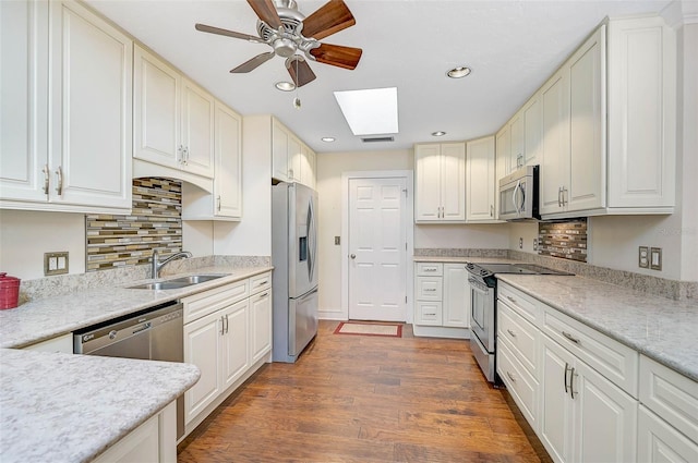 kitchen with sink, a skylight, dark hardwood / wood-style floors, white cabinetry, and stainless steel appliances