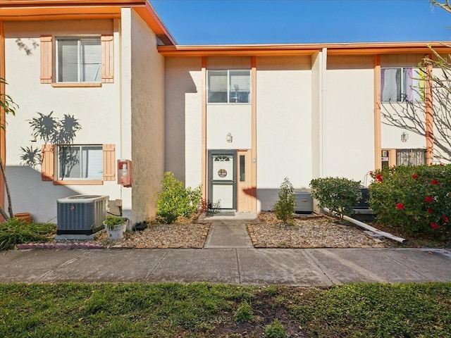 view of exterior entry with cooling unit and stucco siding