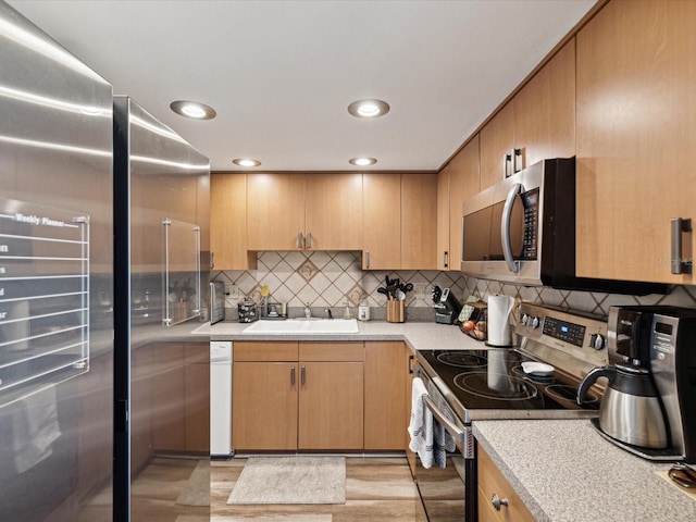 kitchen with tasteful backsplash, appliances with stainless steel finishes, light countertops, and a sink