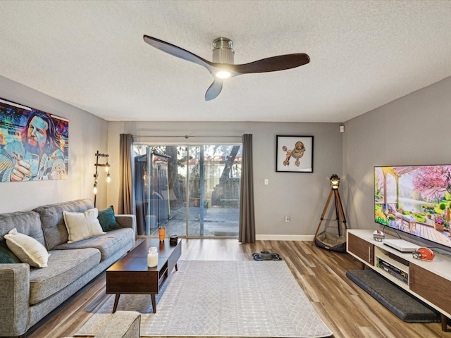 living room with baseboards, a textured ceiling, ceiling fan, and wood finished floors