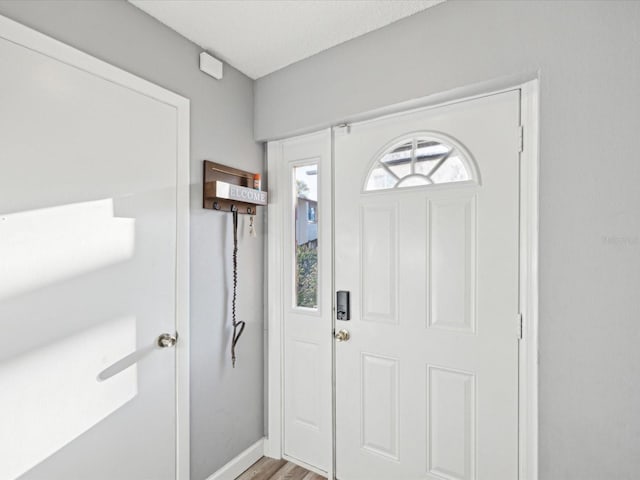 foyer entrance with baseboards and light wood-style flooring