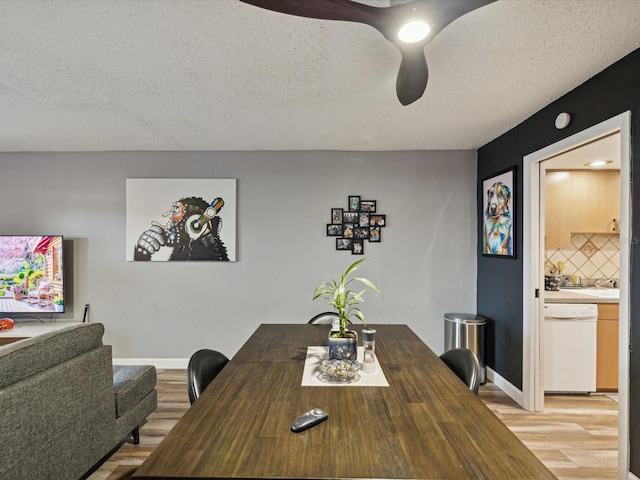 dining room featuring light wood-style flooring, baseboards, and a textured ceiling