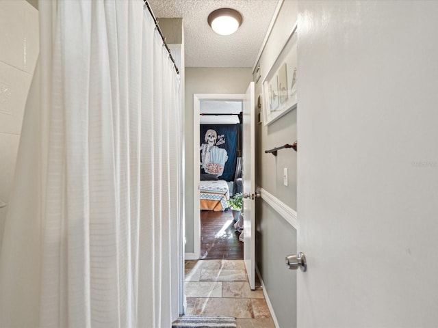 hall featuring baseboards and a textured ceiling