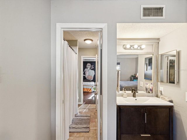 bathroom with visible vents, a textured ceiling, connected bathroom, and vanity