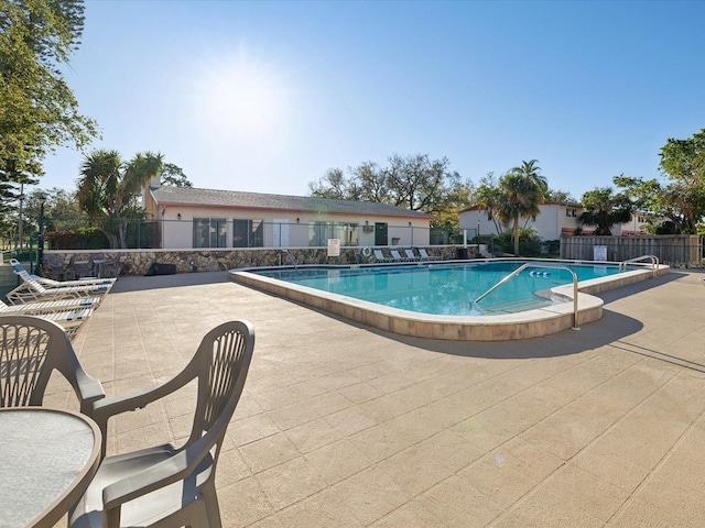 community pool with fence and a patio area