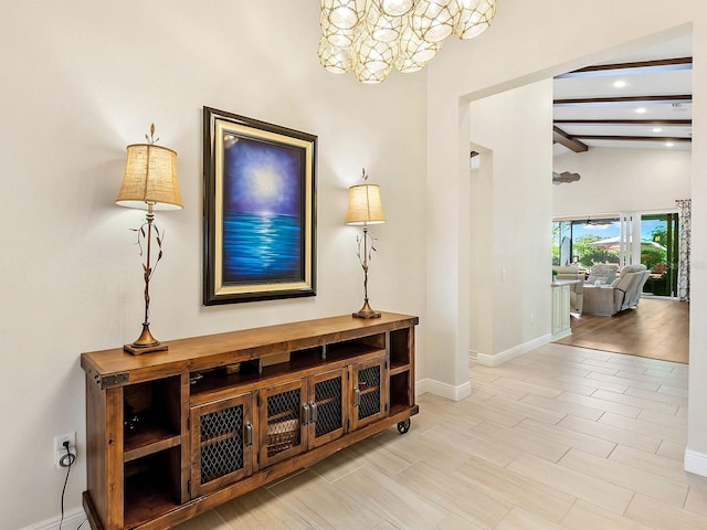 corridor featuring a notable chandelier and vaulted ceiling with beams