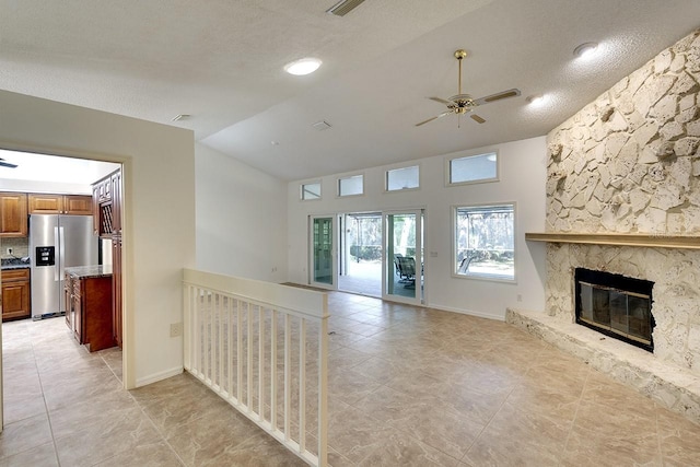 unfurnished living room with a fireplace, a textured ceiling, ceiling fan, and lofted ceiling