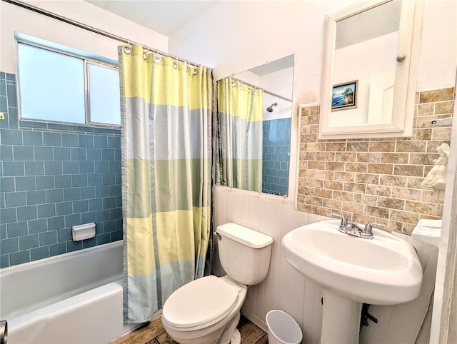 bathroom with toilet, shower / tub combo with curtain, and a sink