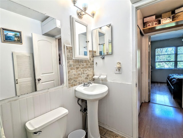 ensuite bathroom featuring a wainscoted wall, toilet, wood finished floors, and ensuite bathroom