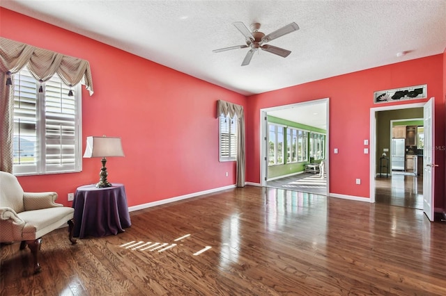 sitting room with a textured ceiling, ceiling fan, and dark wood-type flooring