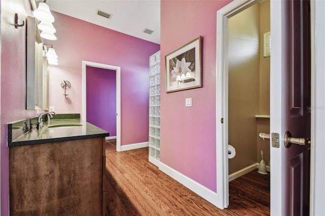 bathroom with hardwood / wood-style floors, vanity, and toilet