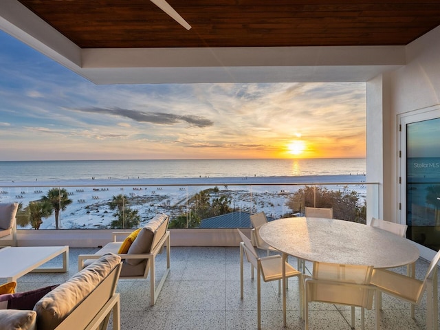 balcony with a view of the beach, a water view, and an outdoor living space