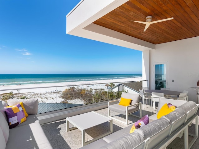 balcony featuring a ceiling fan, an outdoor hangout area, a water view, outdoor dining area, and a view of the beach