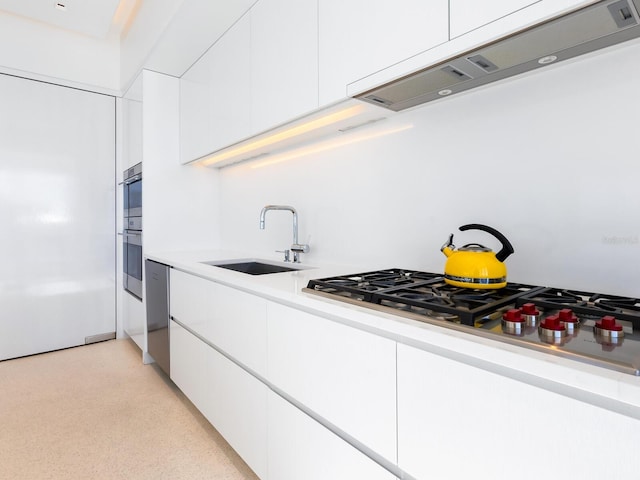 kitchen featuring light countertops, white cabinets, a sink, modern cabinets, and under cabinet range hood