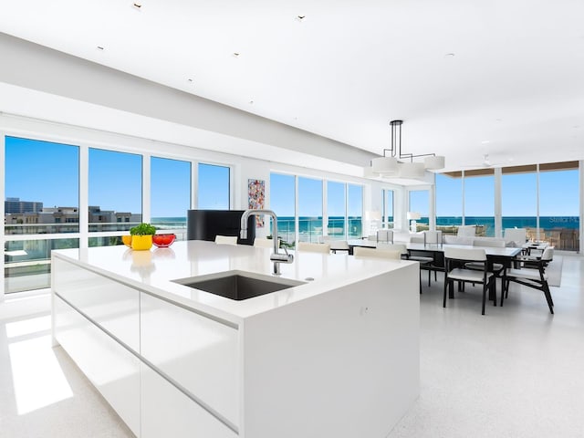 kitchen with an island with sink, modern cabinets, light countertops, white cabinetry, and a sink