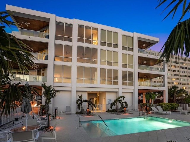 rear view of property featuring a patio, a community pool, and stucco siding