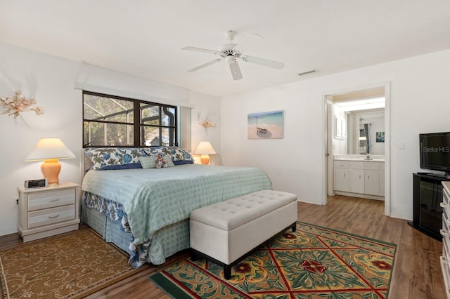 bedroom with hardwood / wood-style floors, ceiling fan, and ensuite bath