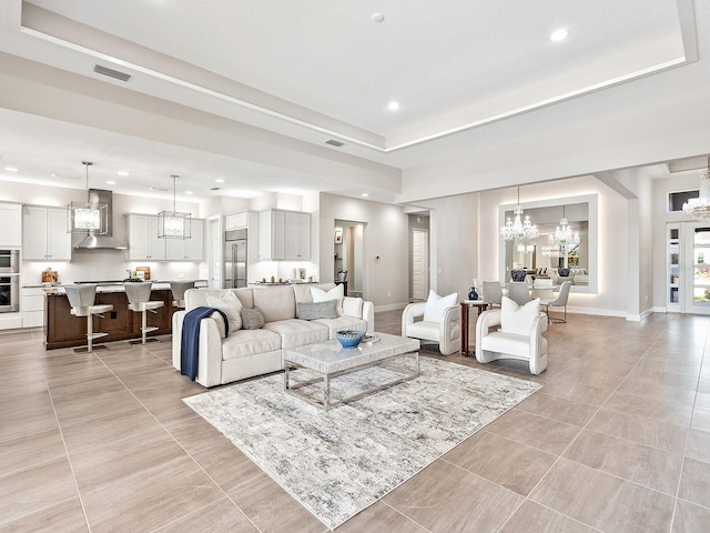 living room with a raised ceiling, light tile patterned flooring, and a notable chandelier