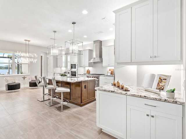 kitchen with white cabinetry, a kitchen island with sink, and wall chimney exhaust hood